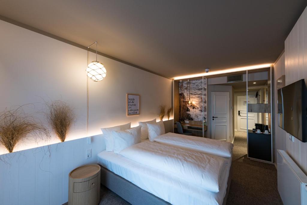 a bedroom with a large white bed and a television at Hafenhotel zu Putbus in Putbus