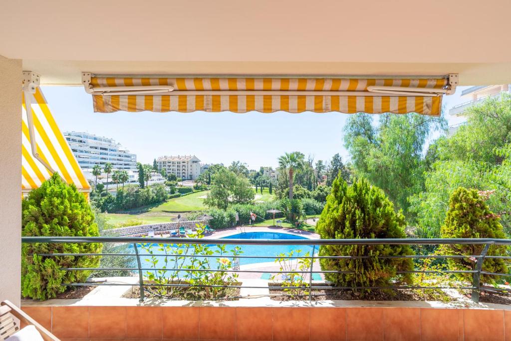 a balcony with a view of a pool and trees at Letmalaga Campos de Guadalmina in Marbella