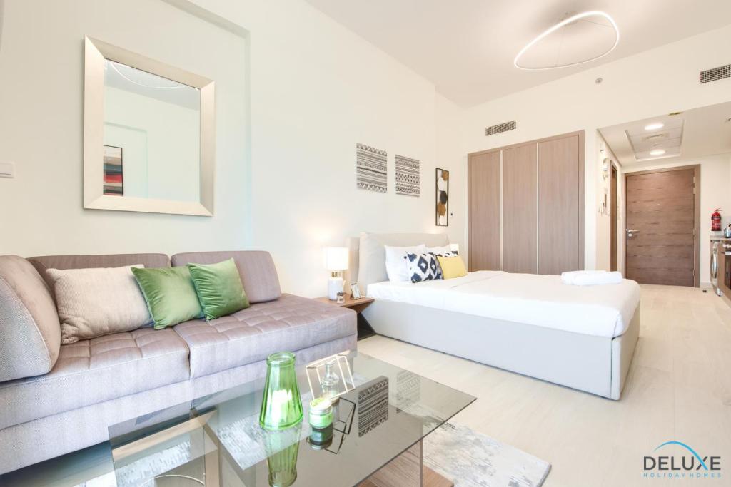 salon z łóżkiem i kanapą w obiekcie Homely Studio in Azizi Aliyah Residence Al Jadaf by Deluxe Holiday Homes w Dubaju