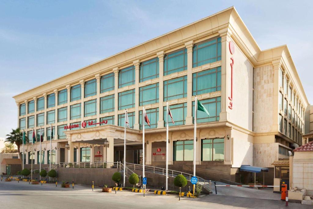 a large building with flags in front of it at Ramada by Wyndham Hotel Riyadh in Riyadh