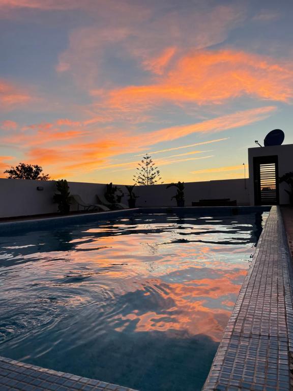 a swimming pool with a sunset in the background at Picasso - Luxury apartment with swimming pool in Casablanca