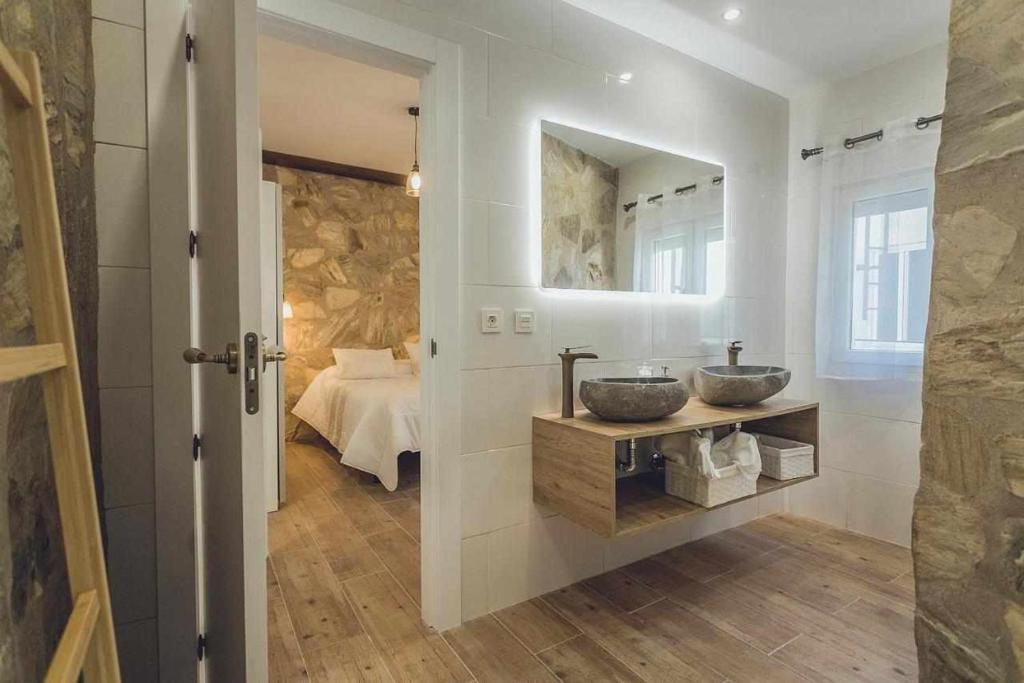 a bathroom with two sinks and a bedroom at Alojamiento Suit Royal in Úbeda