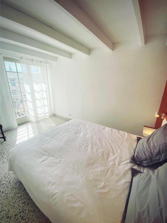 un lit blanc dans une chambre avec une fenêtre dans l'établissement Tutto Mio, à Villeneuve-lès-Avignon