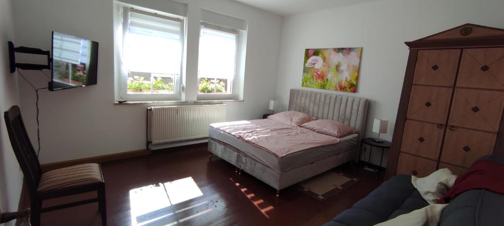 a bedroom with a bed and a couch and two windows at Gästewohnung in Cottbus-Klein Ströbitz in Cottbus