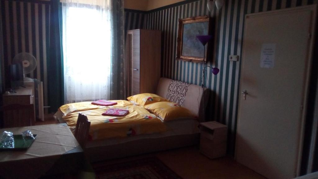 a bedroom with a bed with yellow sheets and a window at Jocó Panzió in Nyíregyháza