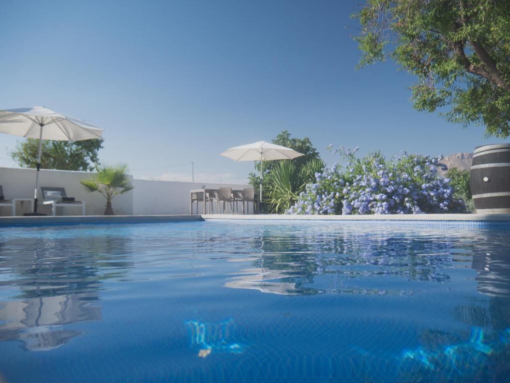 una piscina con agua azul y sombrillas en Boutique Bed & Breakfast Casa Paco - adults only, en Vélez Rubio