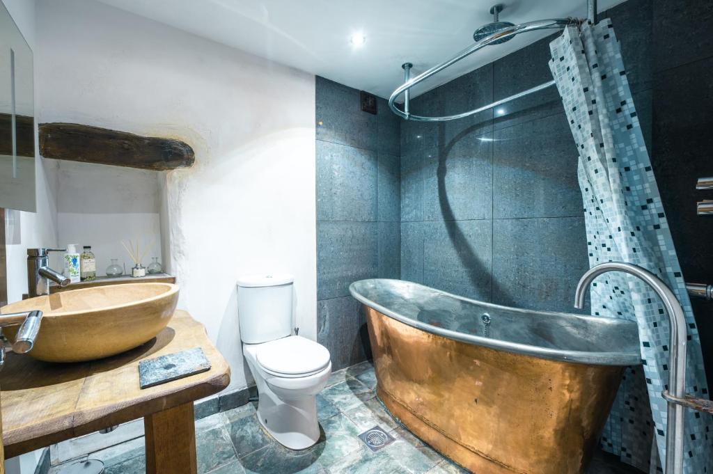 a bathroom with a copper tub and a toilet at St Davids Hideaway with Roll-top Bath & Log Burner in St. Davids