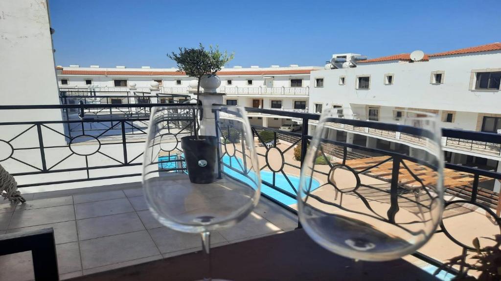 2 copas de vino sentadas en la parte superior de un balcón en Paramount Gardens Resorts C201 en Lárnaca