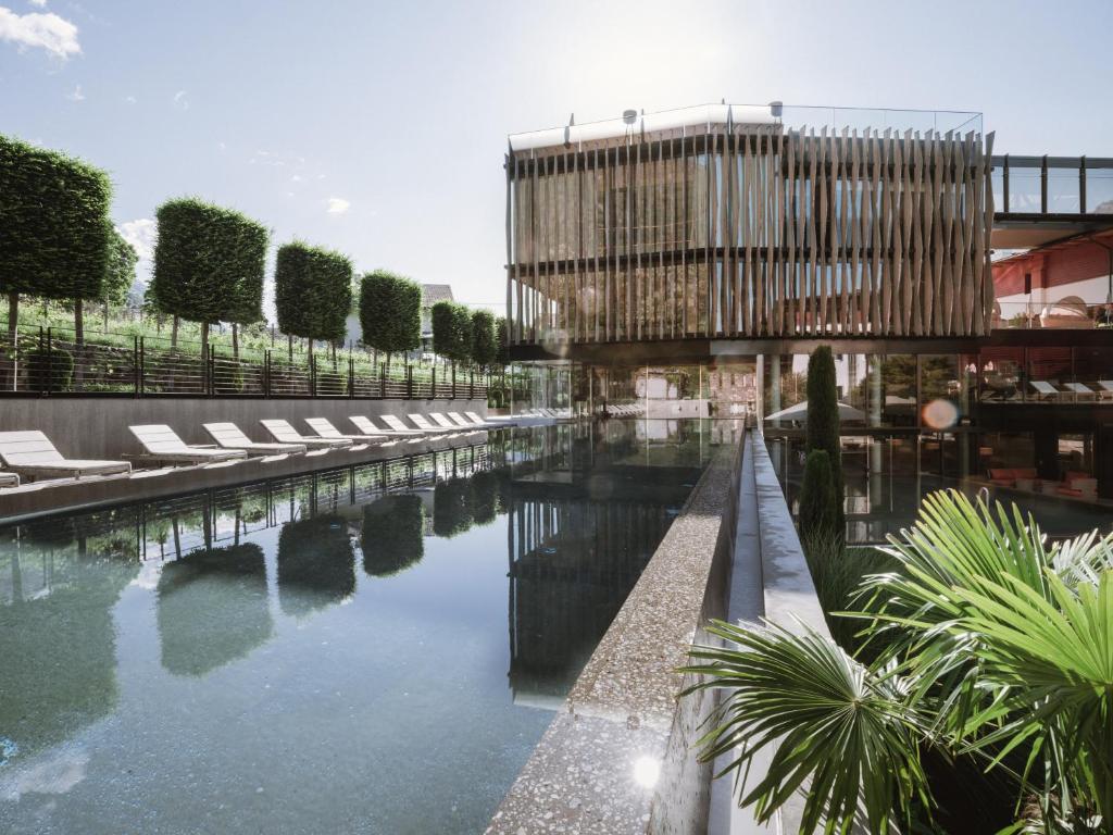 una piscina de agua con tumbonas y un edificio en Lindenhof Pure Luxury & Spa DolceVita Resort, en Naturno