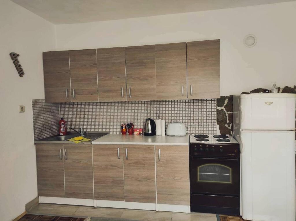 a kitchen with wooden cabinets and a white refrigerator at Ajsha Guesthouse in Jajce