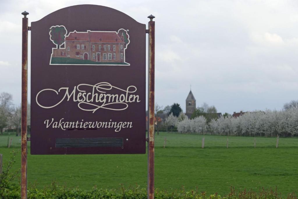 un cartello per un museo con un edificio in un campo di Meschermolen 8 a Eijsden