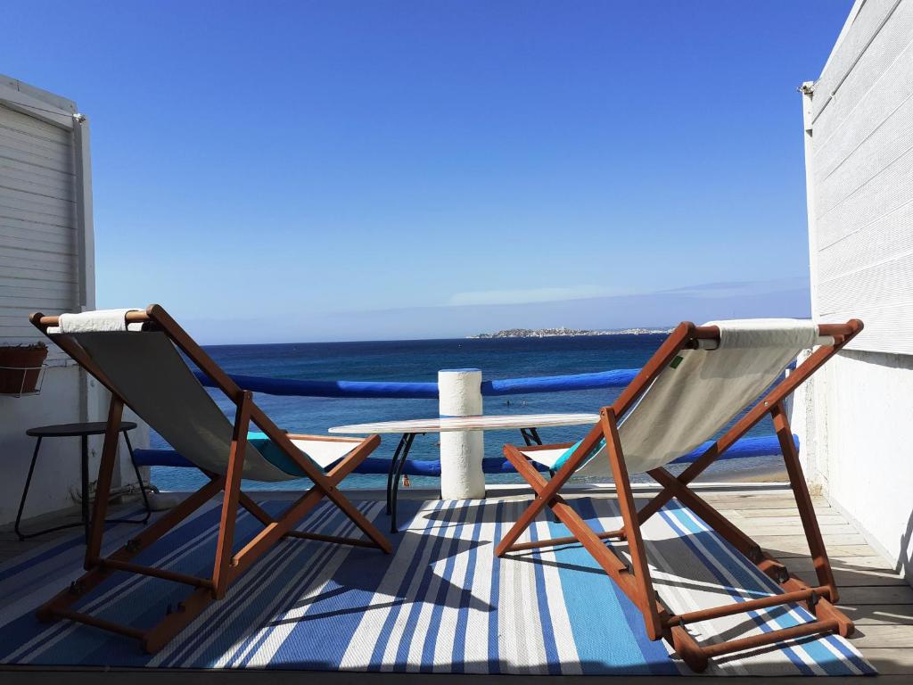 two chairs and a table on a balcony with the ocean at Chouette Cabanon sur la plage vue mer et terrasse privée in Marseille