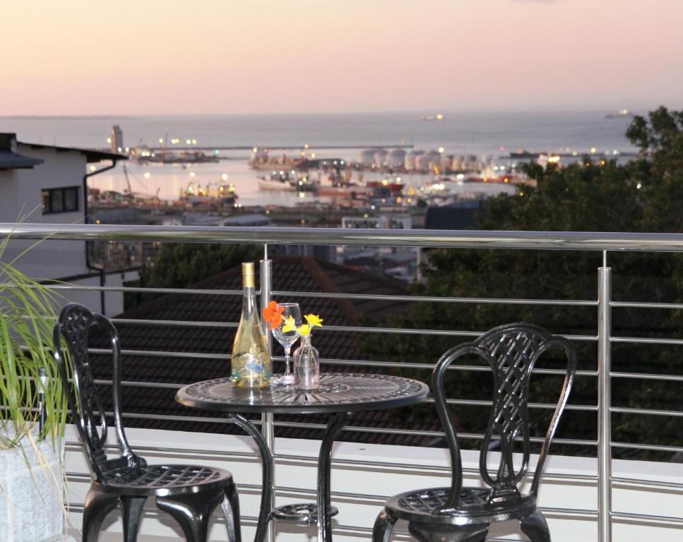 una mesa y sillas en un balcón con vistas en Harbour View Guest Suite, en Ciudad del Cabo