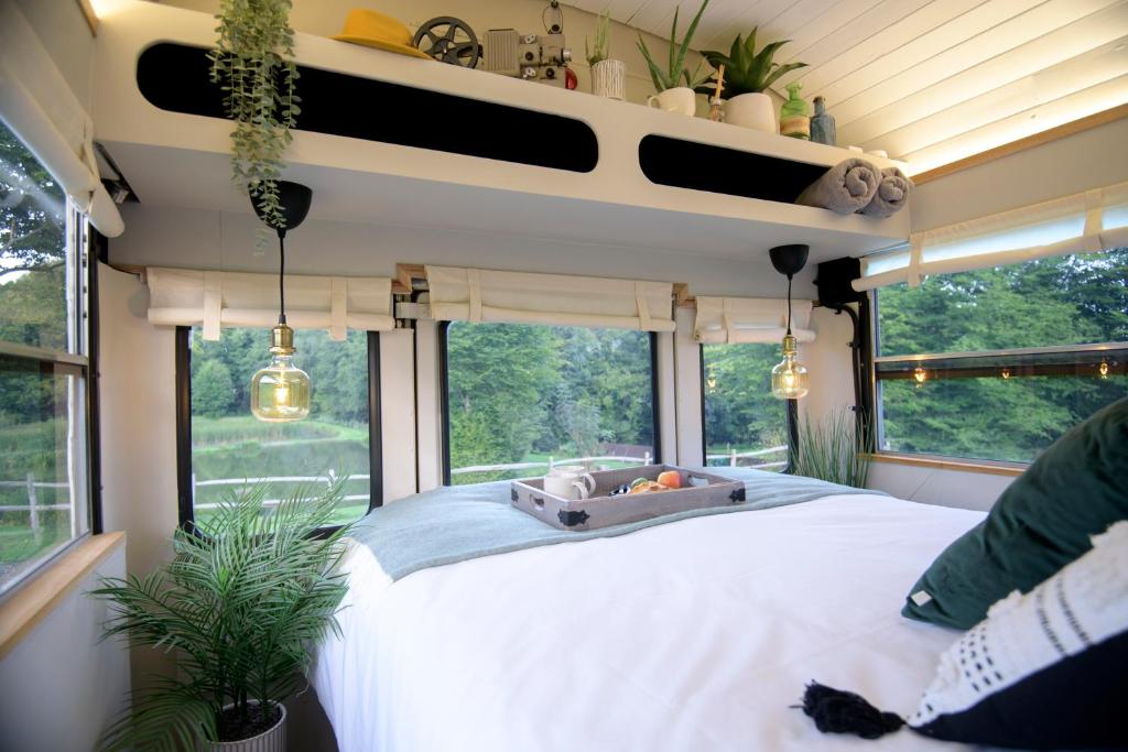 1 dormitorio con 1 cama grande y algunas ventanas en American School Bus Retreat with Hot Tub in Sussex Meadow, en Uckfield