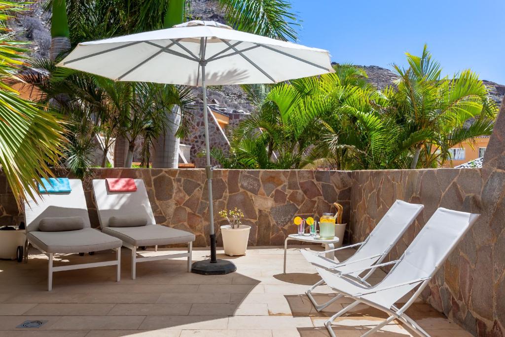 un patio con 2 sillas y una sombrilla en Zen Home Tauro, en La Playa de Tauro