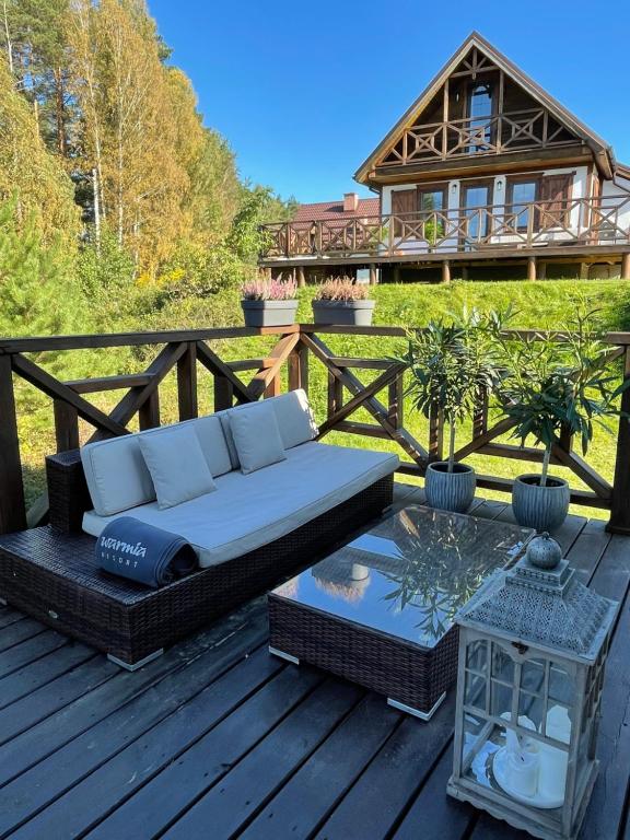 un canapé et une table sur une terrasse avec une maison dans l'établissement Warmia Resort, à Woryty