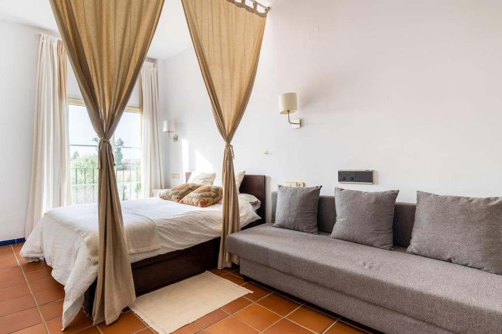um quarto com uma cama e um sofá em GINVA - Apartahotel El Rocio-Doñana em El Rocío