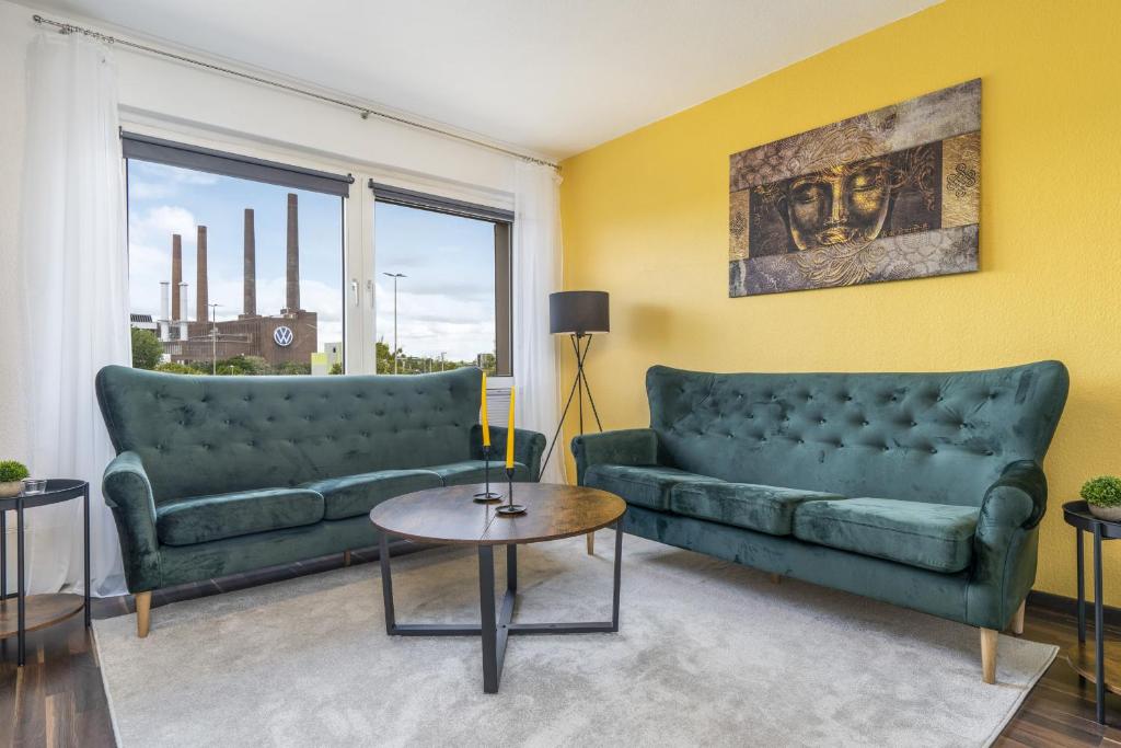 una sala de estar con 2 sofás verdes y una mesa. en FREE LIVING - VW näher geht nicht, Parkplatz, Küche, Wlan en Wolfsburg