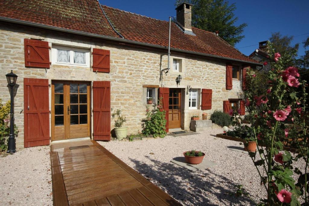a stone house with red doors and a courtyard at Fleurey la Cabotaine in Mont-Saint-Jean