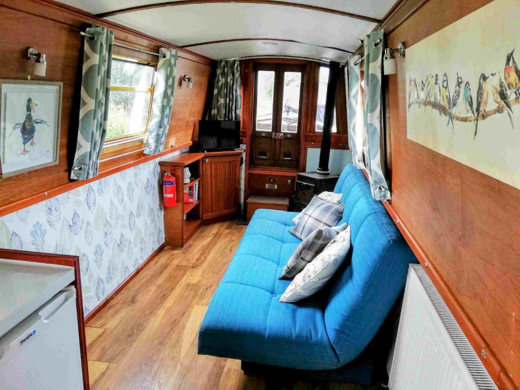 uma sala de estar com um sofá azul num vagão de comboio em Narrow Escape - 50ft Boat on the Grand Union Canal, near Tring em Tring