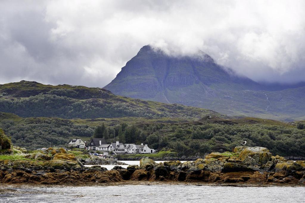 a mountain in the distance with a house in the foreground at Kylesku Hotel in Kylestrome