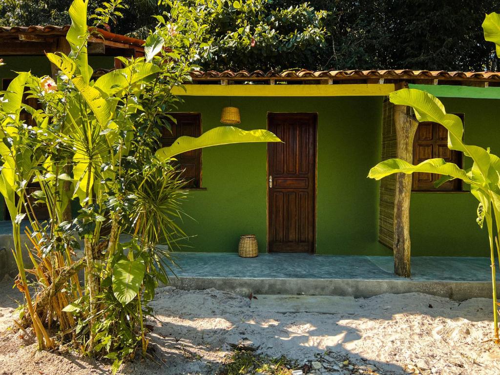 a green house with a wooden door in front at Pousada Moreré in Ilha de Boipeba