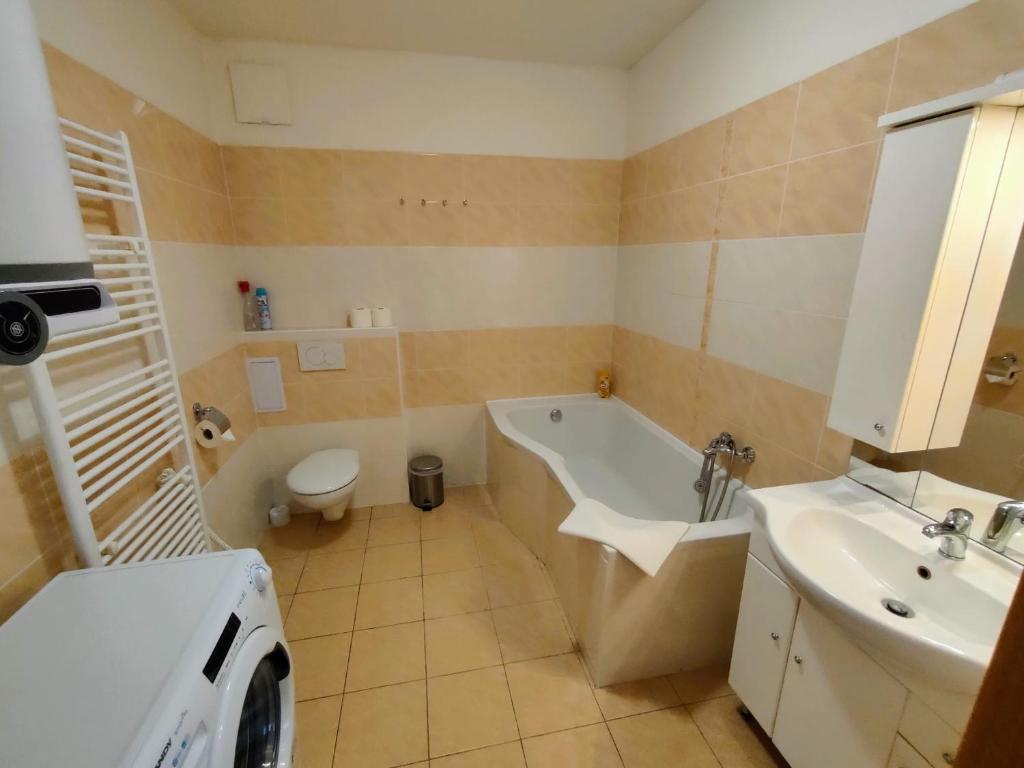 W łazience znajduje się wanna, umywalka i pralka. w obiekcie Bohemica Apartments w mieście Děčín