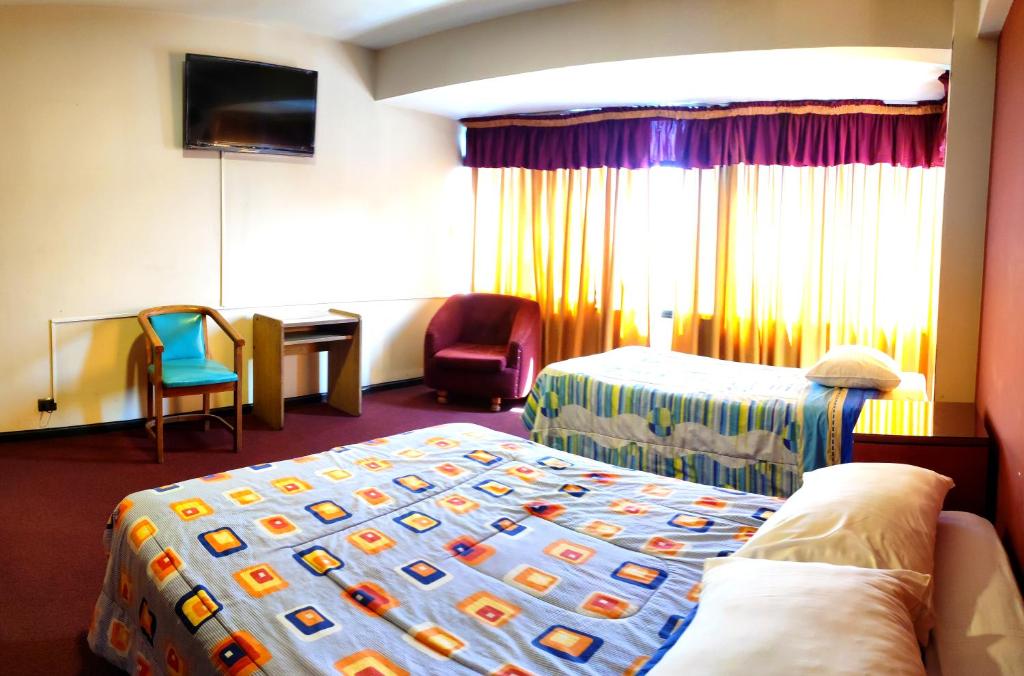 Habitación de hotel con 2 camas, escritorio y TV. en Unión Plaza Hotel, en Cochabamba