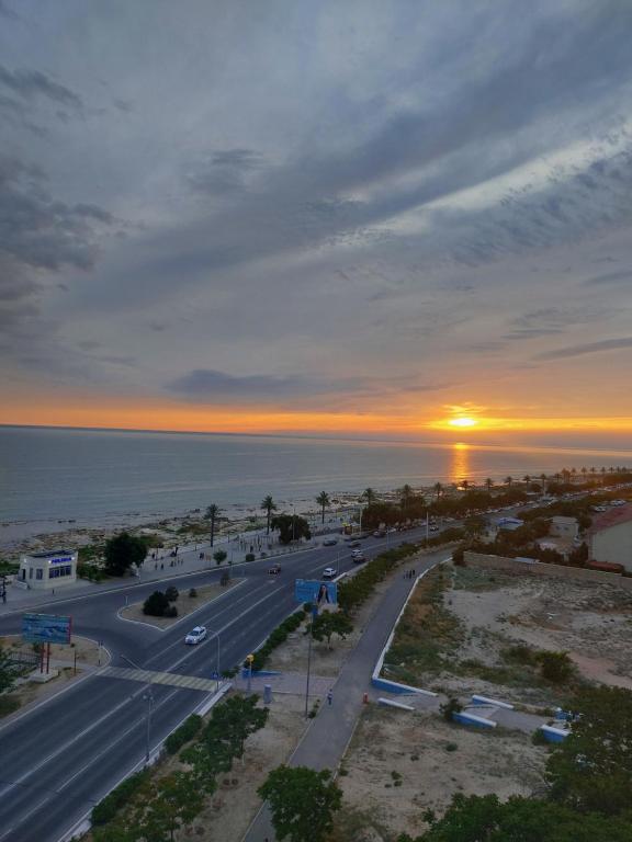a road in front of the ocean with a sunset at У моря in Aktau