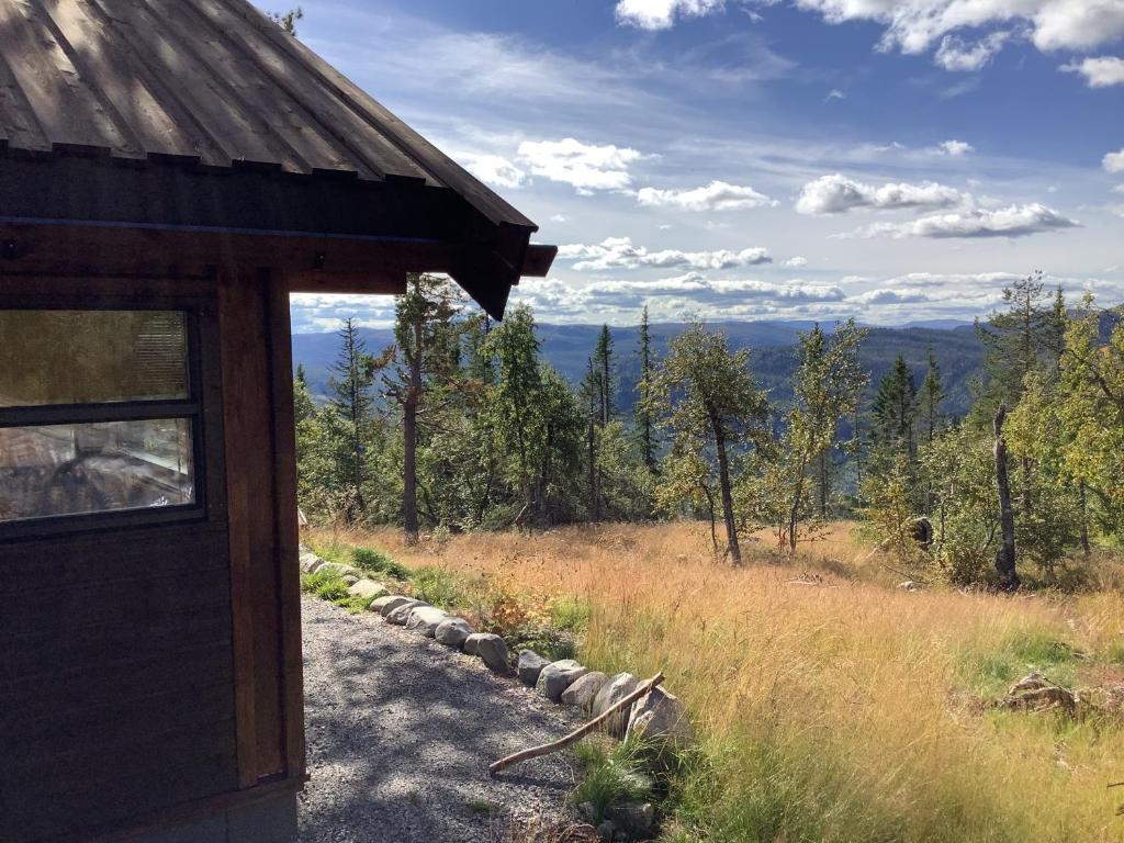 um edifício com vista para um campo e árvores em Skarehaug - koselig hytte med 3 soverom em Skadeland