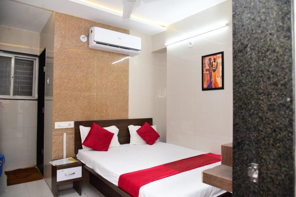 a bedroom with a bed with red pillows at Nivant Lodge in Solapur
