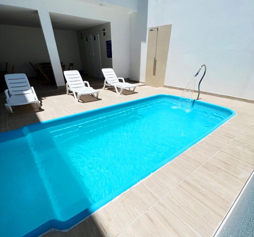 una piscina con 2 sillas y una lámpara en Pousada Praia Bela, en Maragogi