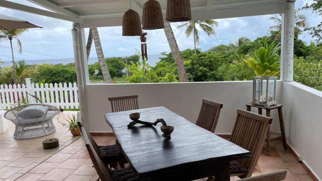 a wooden table on a porch with a view of the ocean at Le M Hotel Marie Galante in Beauregard