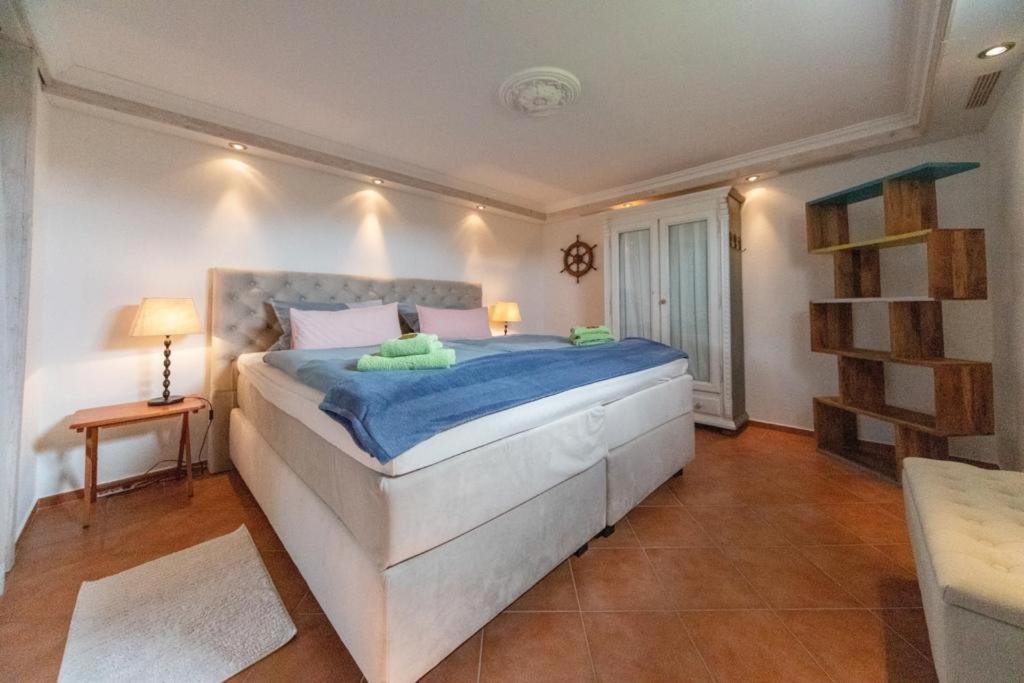 1 dormitorio con 1 cama blanca grande con sábanas azules en Kajüte, en Ihlow