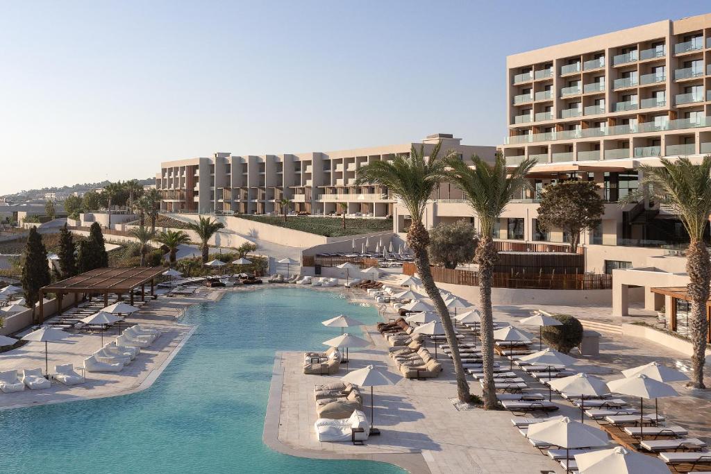 羅德島卡利地亞的住宿－Helea Lifestyle Beach Resort，一个带椅子和遮阳伞的游泳池的度假酒店