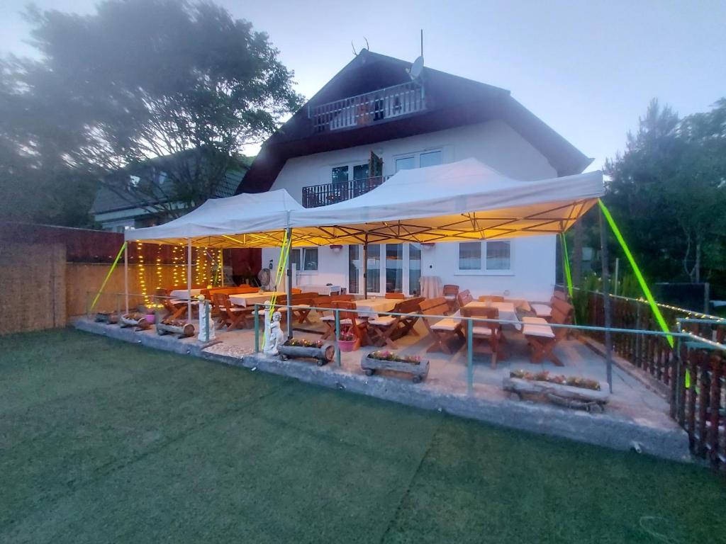 a white house with a patio with tables and chairs at Attila's Guest House in Budaörs