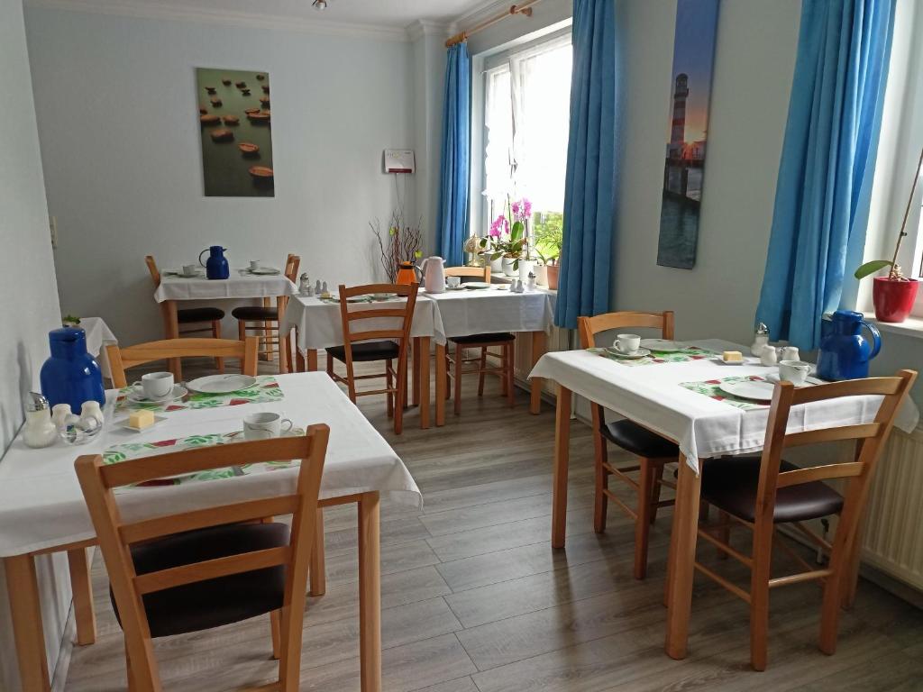 Un comedor con mesas y sillas blancas. en Pension Abendsonne, en Büsum