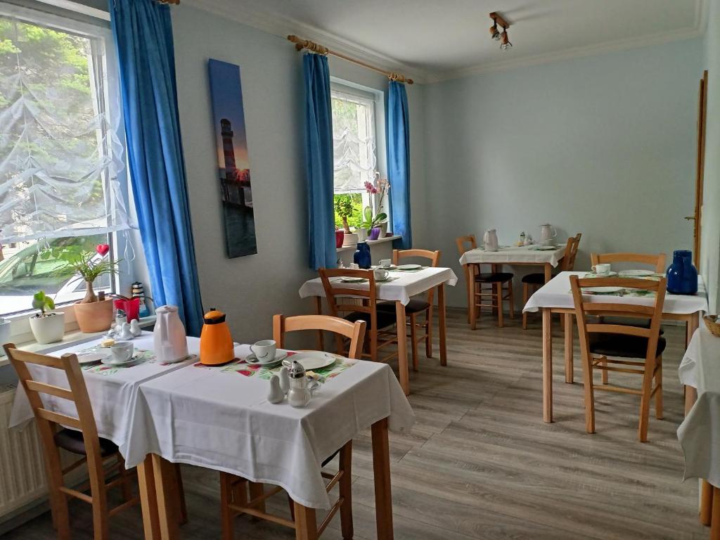 ein Restaurant mit weißen Tischen, Stühlen und Fenstern in der Unterkunft Pension Abendsonne in Büsum