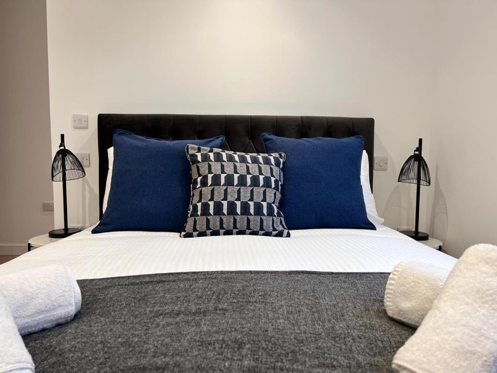 a bed with blue and white pillows and two lamps at Chapel - Central Studio Apartment in Bath