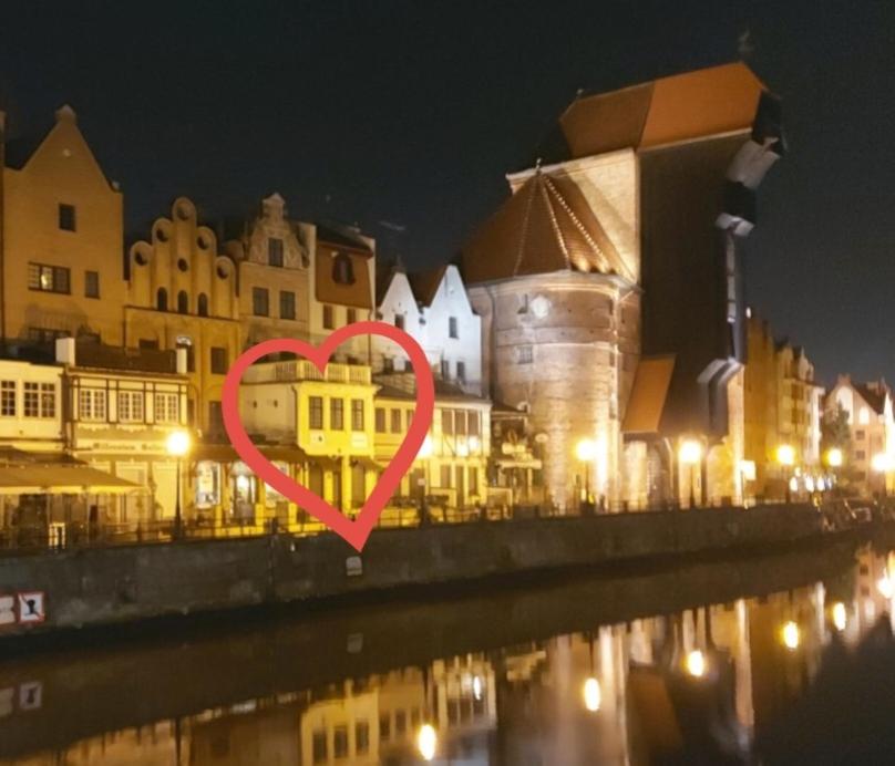 un signo cardiaco frente a una ciudad por la noche en Apartamenty Żuraw en Gdansk