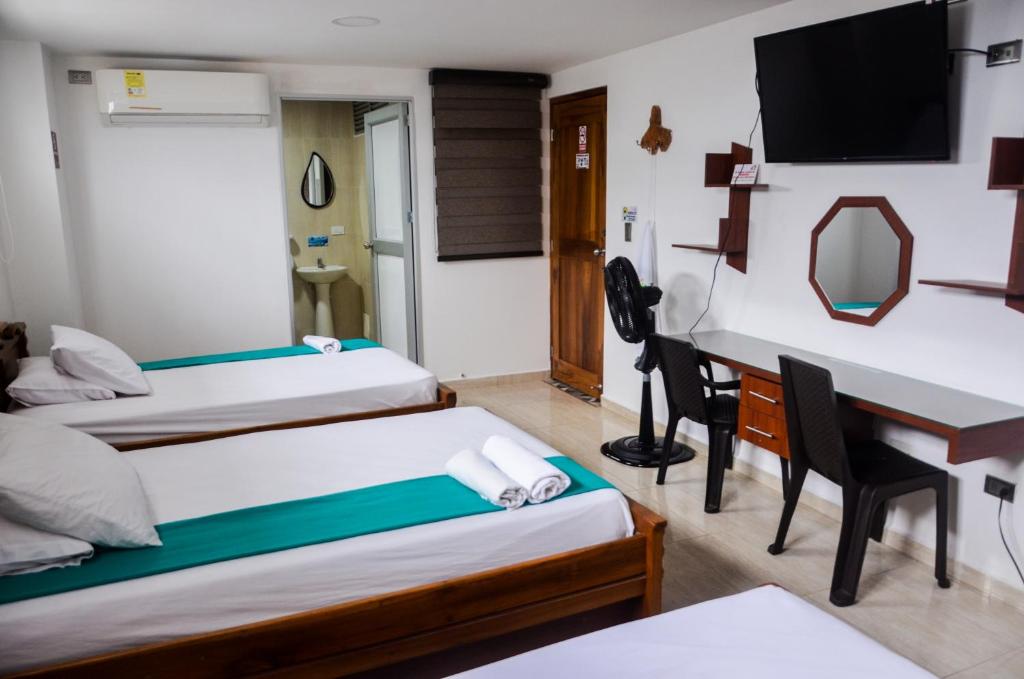 Habitación de hotel con 2 camas y escritorio en Hotel Shaira 2 en Quibdó