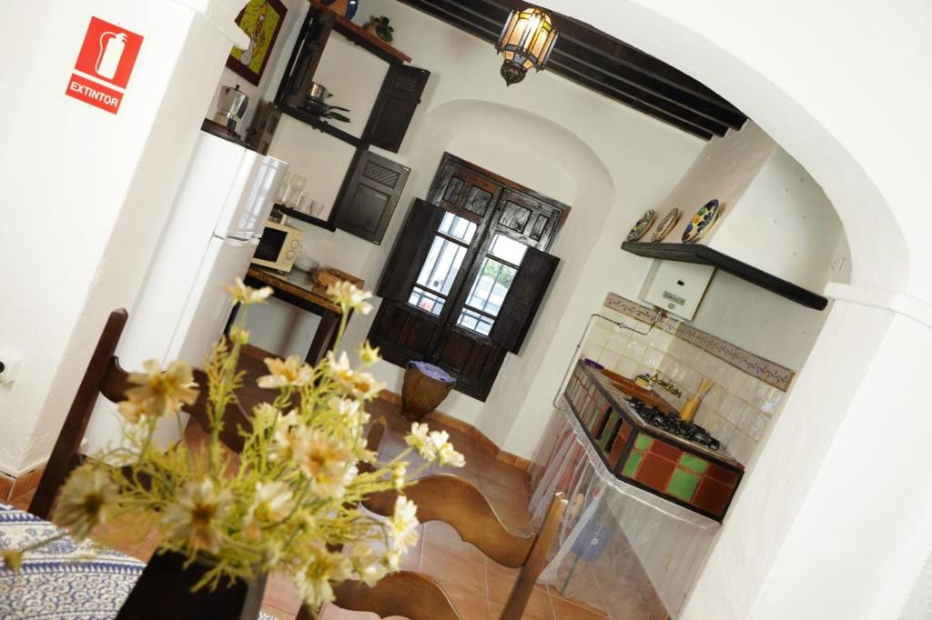 una sala de estar con una escalera y una cocina con un jarrón de flores en Mascotas 2 en Benaocaz