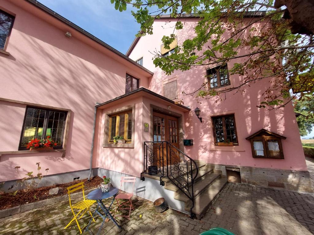 een roze huis met een tafel en stoelen ervoor bij Auberge De La Foret - Logis in Vendenheim