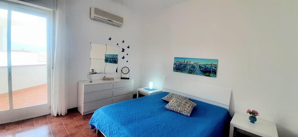 a bedroom with a blue bed and a balcony at da subito libera Dune Dorate,Tramonti Infiniti la tua oasi di pace in Dune ! Aprile al Mare in Appartamento con vista panoramica e WiFi Casa Vacanza Vista Mare in Sicilia Relax e Tramonti Unici in Alcamo Marina