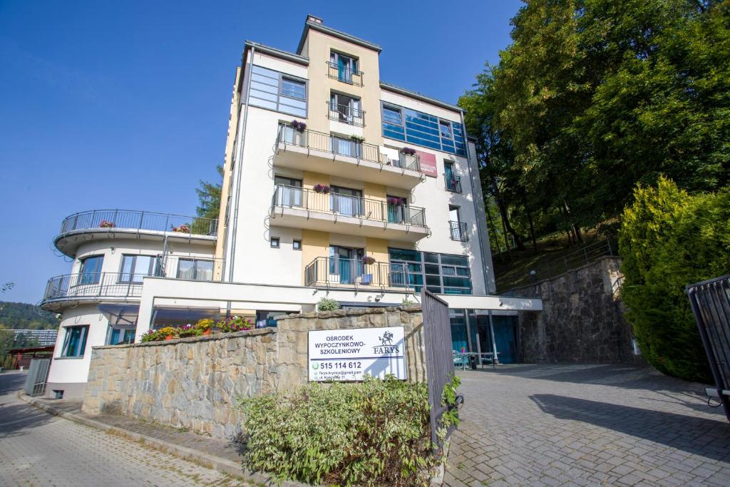 un edificio blanco alto con un cartel delante en Farys - świetna lokalizacja, sauna, jacuzzi, piękne widoki z okien, en Krynica-Zdrój