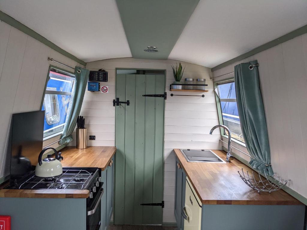 una cocina con una puerta verde en una casa pequeña en Mini Escape - 2 Berth Narrowboat on the Grand Union, Hertfordshire 
