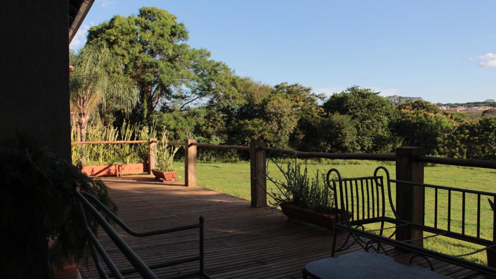 um deque de madeira com dois bancos e um campo em Itaygua Hotel em Ribeirão Preto