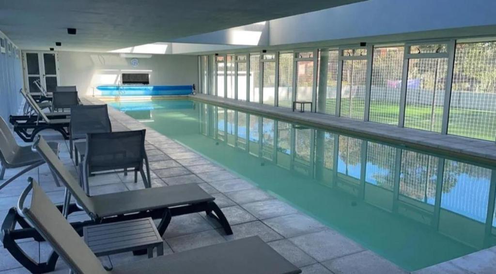 uma piscina com mesas e cadeiras num edifício em Apto en Punta del Este con Piscina Climatizada!! em Punta del Este