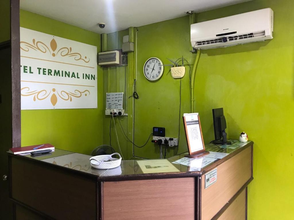 an office with a desk with a clock on a green wall at MOTEL TERMINAL INN in Inanam