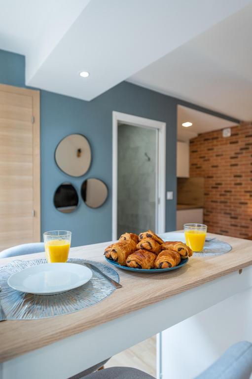 une assiette de pain sur un comptoir avec deux verres de jus d'orange dans l'établissement COSY STUDIO RENOVÉ 150m de MONACO, à Beausoleil